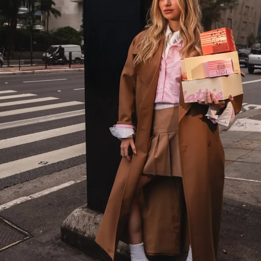 Mulher atravessando a rua com caixas da Flatties nos braços.